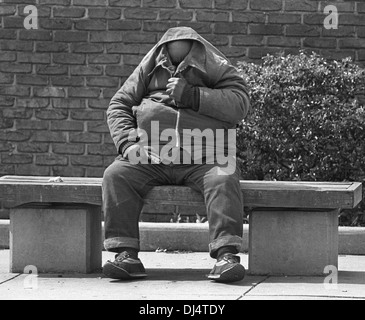 Ein Obdachloser Mann sitzt auf einer Bank versteckt sein Gesicht in Frederick, Maryland, 1988. Foto von Janet Worne. Stockfoto