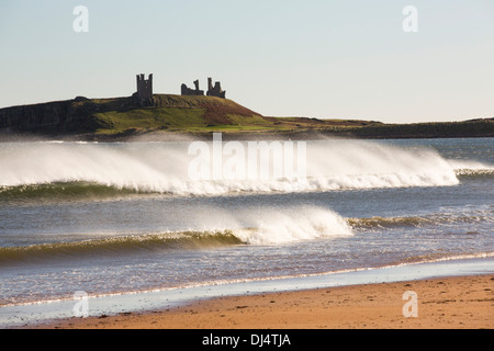 Sprühen Sie bei windigem Wetter von brechenden Wellen, auf der Suche nach Dunstanburgh Castle, Northumberland, UK. Stockfoto