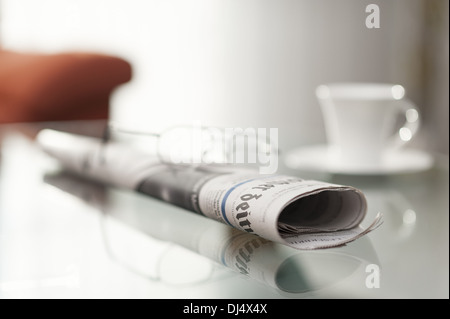 rollte Zeitung sitzt auf einem Couchtisch Stockfoto