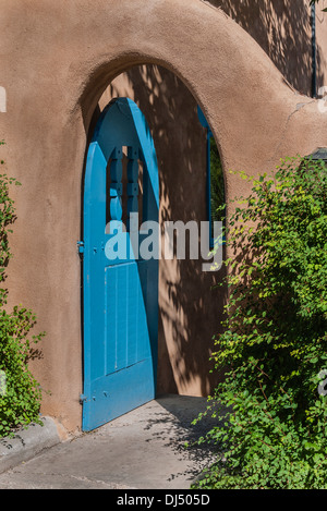 Traditionelle gewölbte Türkis Holztür auf einen Adobe-Wand-Eingang in ein Haus in Santa Fe, New Mexico.