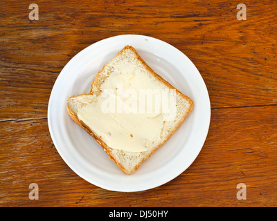 Brot und Butter Sandwich auf weißen Teller auf Holztisch Stockfoto