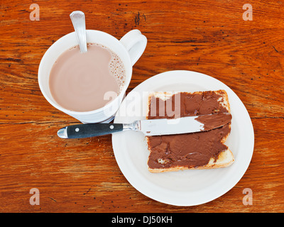 Süßes Sandwich aus frischen Toast mit Nutella, Tabelle Messer und Tasse heißer Schokolade auf Holztisch Stockfoto