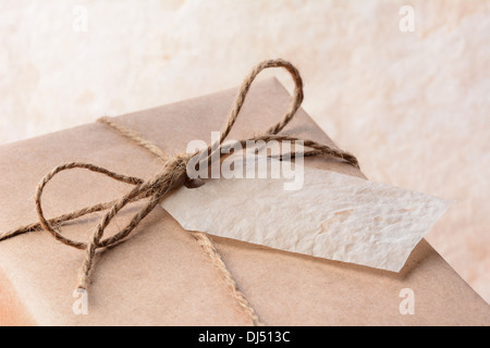 Nahaufnahme von einem braunen Eco freundliche Papier eingewickelt Paket mit Geschenkanhänger. Querformat mit geringen Schärfentiefe. Stockfoto
