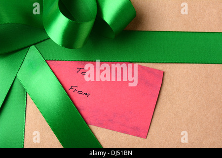 Nahaufnahme einer Geschenkanhänger auf ein Weihnachtsgeschenk. Das Paket ist umhüllt von braunen Normalpapier und Green Ribbon. Stockfoto