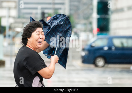 Ein chinesischer Tourist in Hongkong kämpfen mit ihrem Schirm während der Taifun Usagi Stockfoto