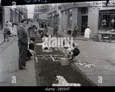 1950s, historisch, Bewohner einer französischen Stadt draußen in einer Straße bereiten die Blumenfeste für den lokalen Karneval vor. Stockfoto