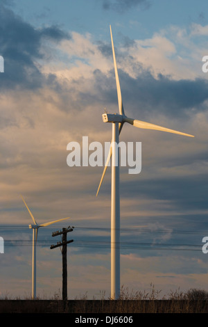 Zwei wind-Turbinen und eine alte Linie Strommast und Drähte nach Sonnenaufgang. Wolken im Hintergrund. Stockfoto