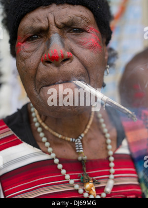 Ältere Frau Singsing Fraktion, Goroka Show, Papua New Guinea Rauchen handmade Tabak-Zigarette Stockfoto