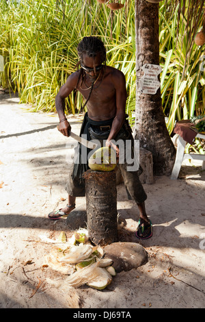 Obstverkäufer am Strand von Guadeloupe peeling eine Kokosnuss mit einer machete Stockfoto