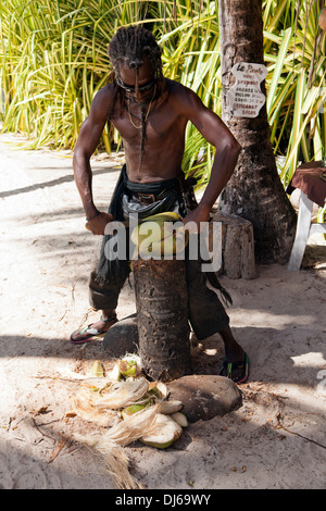 Obstverkäufer am Strand von Guadeloupe peeling eine Kokosnuss mit einer machete Stockfoto