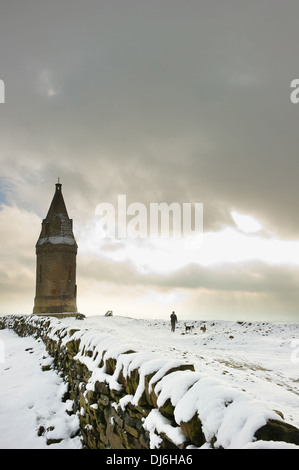 Ein Mann, der Hunde im Schnee in der Nähe von Hartshead Pike, Ashton-under-Lyne, Greater Manchester. Stockfoto