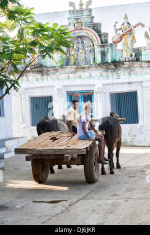 Südindische Männer auf einem Ochsenkarren vor einem hindu Tempel in einem indischen Dorf. Andhra Pradesh, Indien Stockfoto