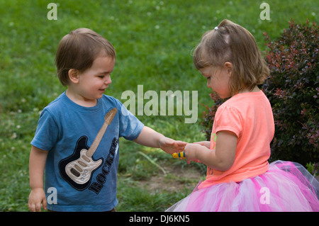 Drei Jahre altes Mädchen und zwei Jahre alten Jungen Spielzeug teilen Stockfoto