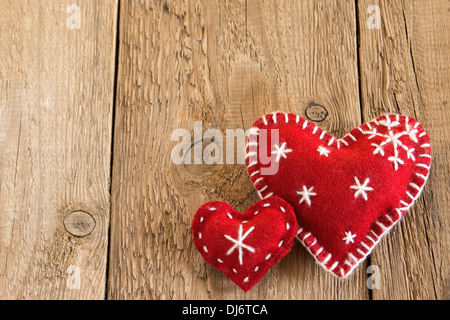 Weihnachten-Konzept (Dekoration). Zwei rote handgefertigte Herzen über rustikalen hölzernen Hintergrund (Textur) großaufnahme, horizontale. Stockfoto