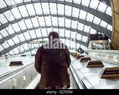 Mann auf Rolltreppe mit "Bitte stehen auf der rechten Seite" Zeichen bei Heron Quays DLR (Docklands Light Railway) Station - London Stockfoto