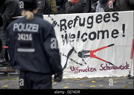 Berlin, Deutschland. 23. November 2013. Eine Polizistin steht vor ein Banner mit dem Logo "Flüchtlinge von Demonstranten, die protest gegen den Neonazi-Marsch in Berlin, Deutschland, 23. November 2013 begrüßen zu dürfen". Unter starken Polizei Schutz der Neonazis von Schoeneweide nach Rudow und Protest gegen die Fremdherrschaft in Berlin gelaufen. Foto: Paul Zinken/Dpa/Alamy Live News Stockfoto