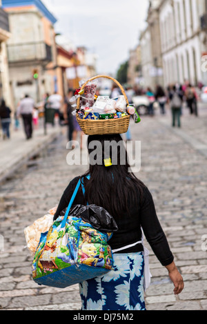 Verkaeufers "mexikanischen Straße" geht durch die Fußgängerzone von Alcala mit ihren waren ausgeglichen auf dem Kopf in Oaxaca, Mexiko. Stockfoto