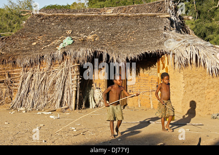 Madagassische Jungs spielen vor strohgedeckten Hütte, Morondava, Madagaskar Stockfoto