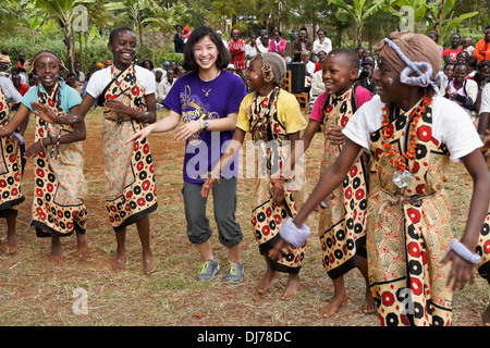 Kikuyu Mädchen tanzen mit chinesisch-amerikanische Mädchen (Tourist), Karatina, Kenia Stockfoto