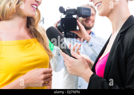 Reporter und Kameramann Film schießen Schauspielerin Interview am Filmset für TV oder Fernsehen Stockfoto