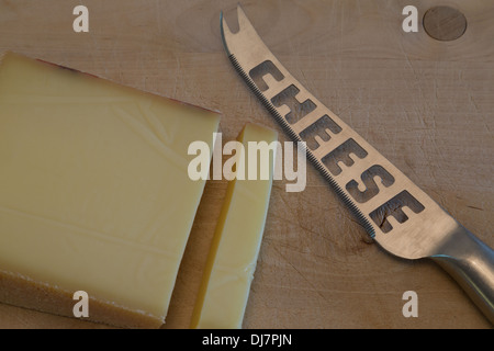 Ein Foto von einigen Schweizer Käse mit einem Käsemesser auf einem Holzbrett. Es ist Gruyere Käse. Stockfoto