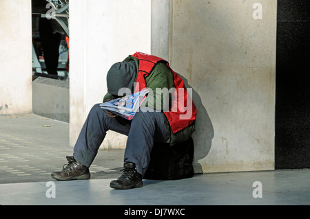 Großes Problem Verkäufer eingewickelt herzlich gegen die Kälte und schlief in der Wintersonne, zentrales London, England UK Stockfoto