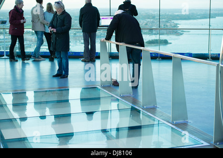 Personen in der 1. Etage des Spinnakers Turm neben Glas Bodenplatte auf die Straßen und Hafen Stockfoto