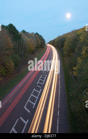 Transport auf der Straße. Schlierenbildung Autolichter vom Berufsverkehr fahren runden Abend der Dorchester umgehen, mit dem Vollmond steigt. Dorset, England, Vereinigtes Königreich Stockfoto