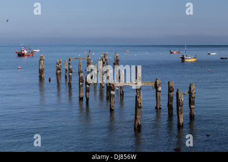 Swanage Bay, Dorset, England. Ruhiges Meer und blauer Himmel. Alte Mole im Vordergrund. Boote vor Anker in Ferne. Stockfoto