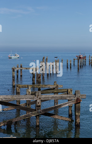 Swanage Bay, Dorset, England. Ruhiges Meer und blauer Himmel. Alte Mole im Vordergrund. Boote vor Anker in Ferne. Stockfoto