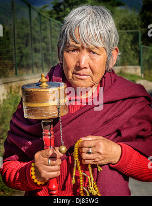 Vertikale Porträt einer bhutanischen alte Dame im Gebet Kleid mit Gebetsmühle in der hand Stockfoto