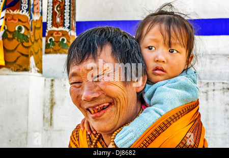 Alte Dame bhutanischen, Großmutter Baby in meschotschek auf dem Rücken tragen Stockfoto