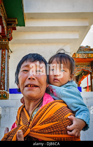 Alte Dame bhutanischen, Großmutter Baby in meschotschek auf dem Rücken tragen Stockfoto