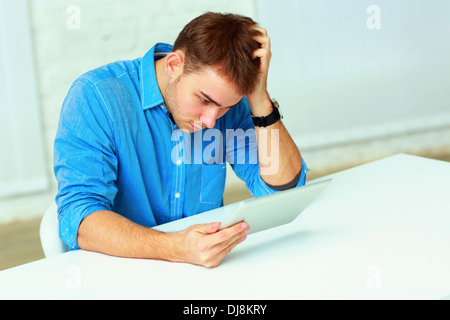 Nachdenklich lässig Jungunternehmer Blick auf den Tablet-Computer im Büro Stockfoto