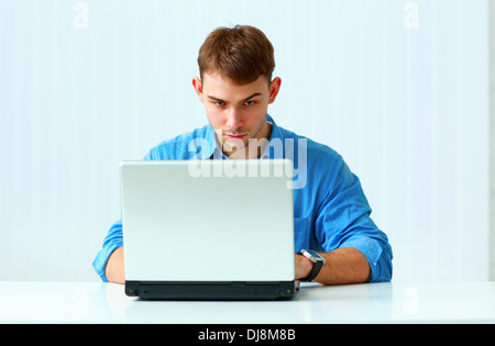 Porträt eines jungen nachdenklich Geschäftsmann mit Laptop im Büro Stockfoto