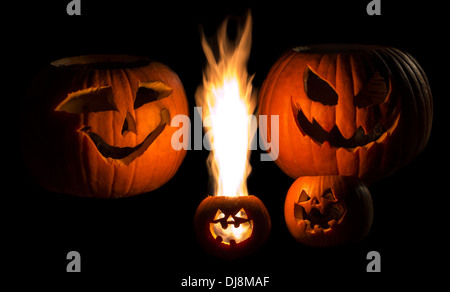 Eine Familie von Jack-o-Laternen isoliert auf schwarz. Das jüngste Kind hat eine große gelbe Flamme, die aus seinem Kopf. Stockfoto