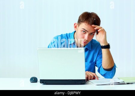 Ernsthafte Jungunternehmer sitzen am Tisch mit Laptop im Büro Stockfoto