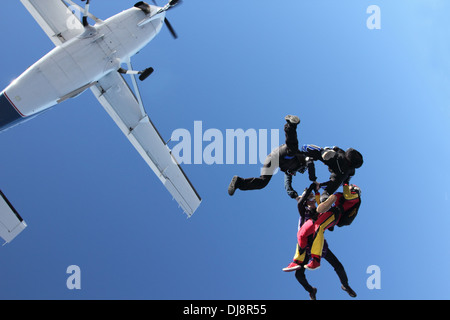 Dieser Fallschirmspringer Team sprang nur aus einem Flugzeug. Sie halten Hand und bilden eine Sternentstehung zusammen in den blauen Himmel. Stockfoto