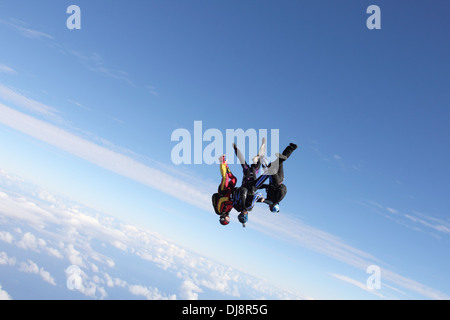 Dieser Fallschirmspringer-Team ist in den blauen Himmel Kopf fliegen vorbei. Sie halten Hand und bilden eine Sternentstehung zusammen über den Wolken. Stockfoto