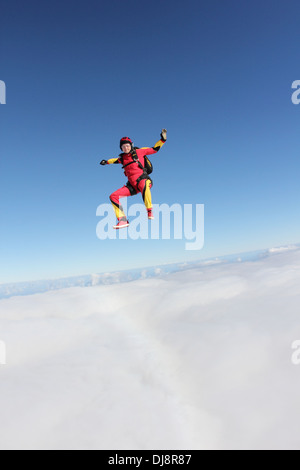 Diese Fallschirmspringer Frau fällt frei in einer Position sitzen über eine große Wolke. Sie lächelt und Spaß in den blauen Himmel. Stockfoto