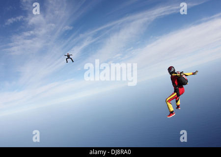 Diese Freefly-Fallschirmspringer fliegen hoch in den blauen Himmel über der Tiefsee. Dabei fliegen sie training sitzen die Position. Stockfoto