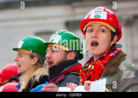 London, 24. November 2013. Aktivisten in grün und Rot Bergbau Helme skandieren Parolen während ihrer laufenden Protest gegen die umstrittenen vorgeschlagenen Goldmine in Rosia Montana in Siebenbürgen. Bildnachweis: Paul Davey/Alamy Live-Nachrichten Stockfoto