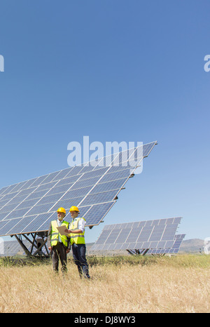 Arbeitnehmer, die durch Sonnenkollektoren in ländlichen Landschaft stehend Stockfoto