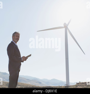 Geschäftsmann Windkraftanlage in ländlichen Landschaft zu bewundern Stockfoto