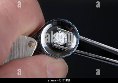 Ein Edelstein durch ein Vergrößerungsglas Lupe geprüft wird. Stockfoto