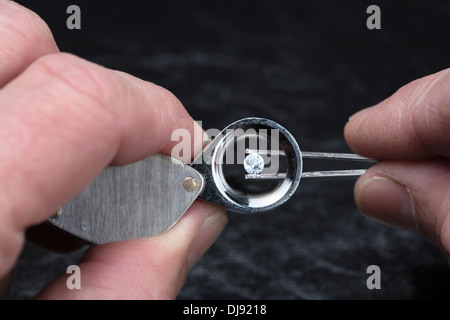 Ein Edelstein durch ein Vergrößerungsglas Lupe geprüft wird. Stockfoto