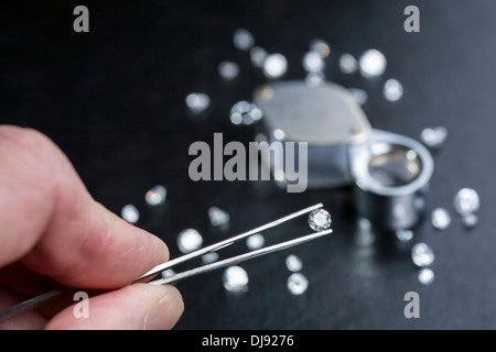 Ein Edelstein durch ein Vergrößerungsglas Lupe geprüft wird. Stockfoto