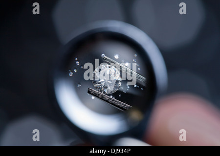 Ein Edelstein durch ein Vergrößerungsglas Lupe geprüft wird. Stockfoto