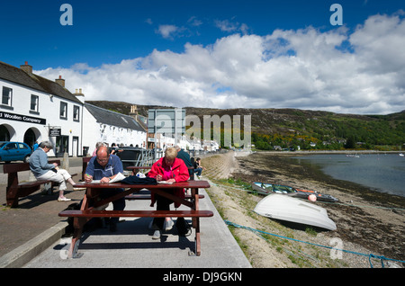 Leute sitzen, entspannen und lesen außerhalb an einem sonnigen Tag Ullapool, Ross & Cromarty, West Schottland UK Stockfoto