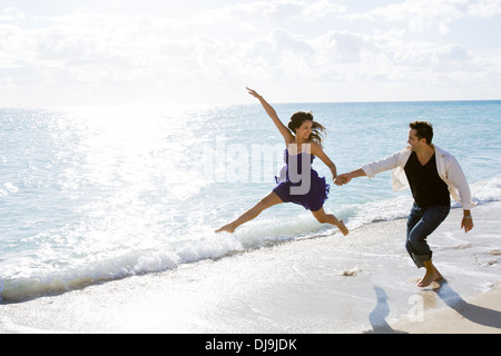 Paar in der Brandung am Strand spielen Stockfoto